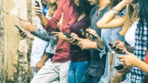 Group of multicultural friends using smartphone outdoors - People hands addicted by mobile smart phone - Technology concept with connected men and women - Shallow depth of field on vintage filter tone